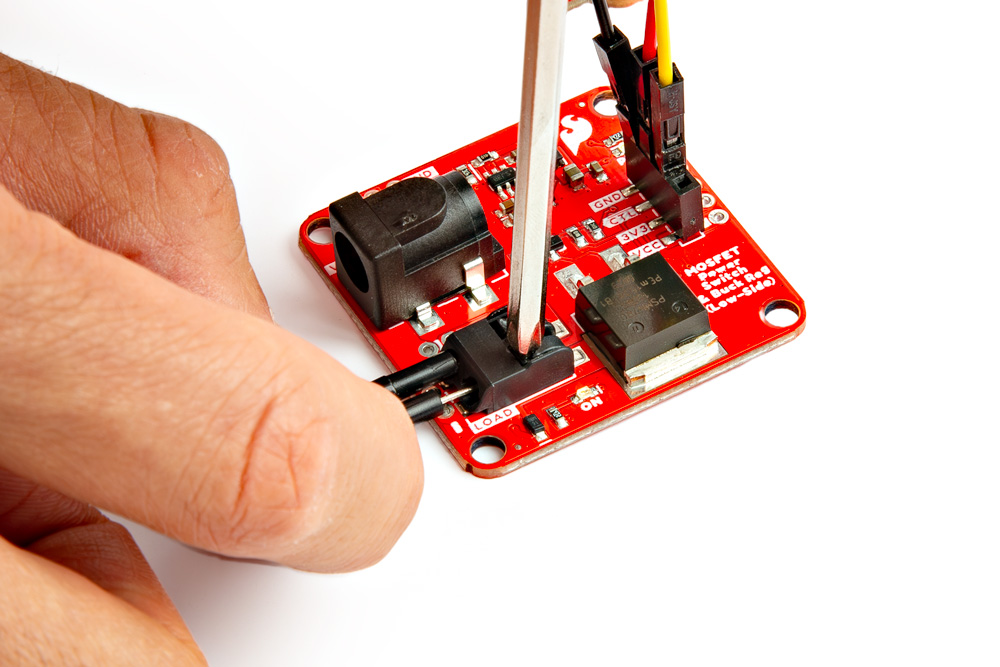 Mini Screwdriver Pushing Down on Poke-Home Connector Tab and Wire Being Inserted